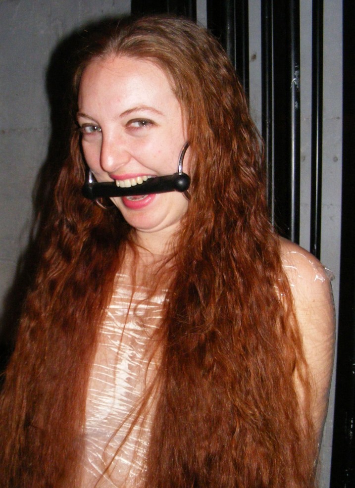 Lacey Field: nude redhead with a bit gag in her mouth.